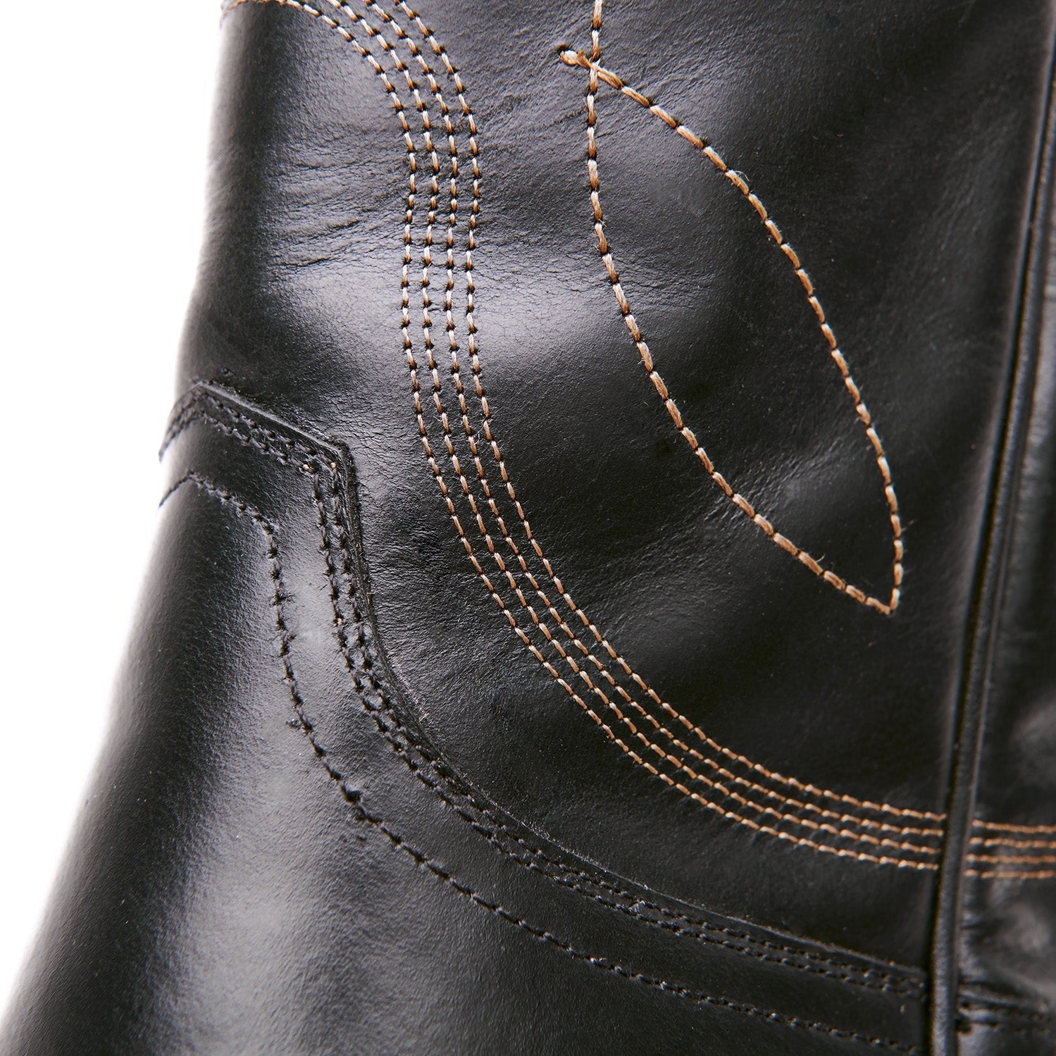 Close-up of black boot upper with curved stitch lines and tan thread