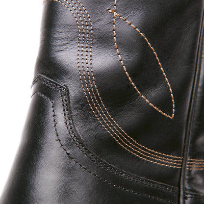 Close-up of black boot upper with curved stitch lines and tan thread