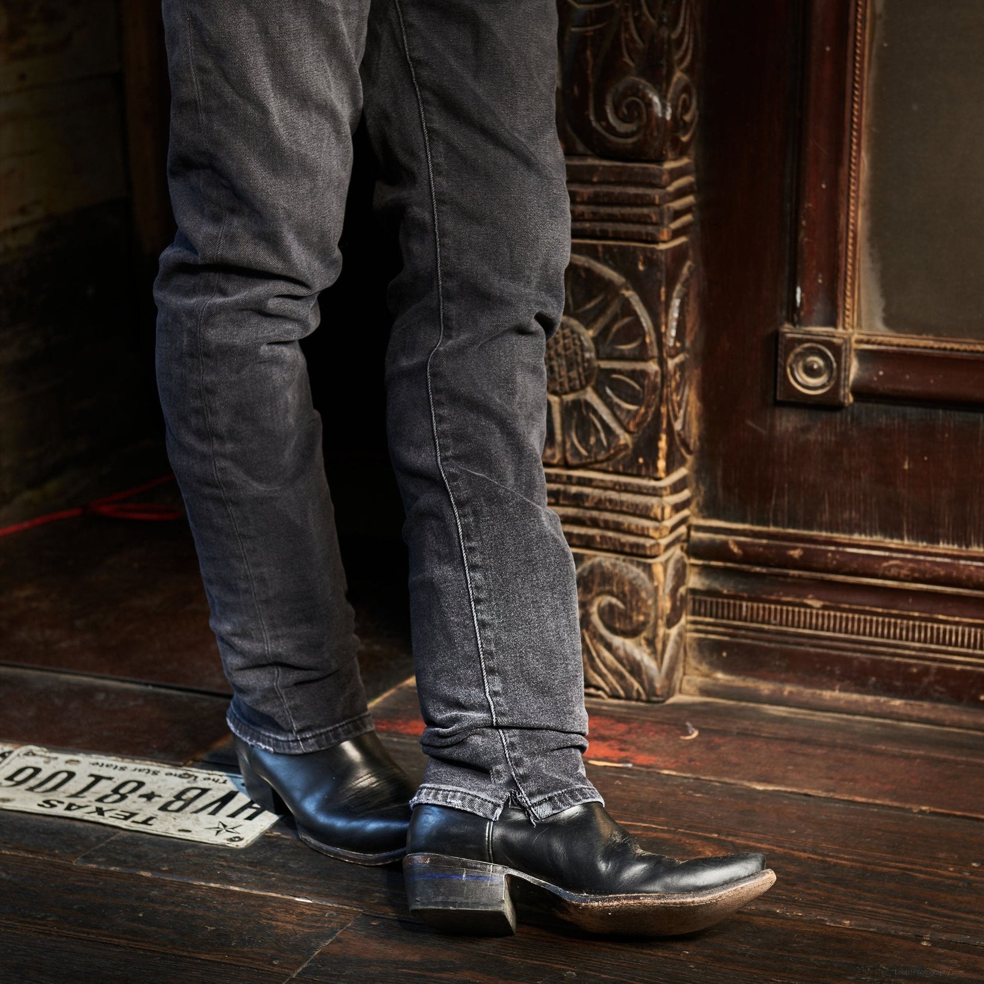 Black cowboy boots with pointed toe and stacked heel, worn with dark jeans
