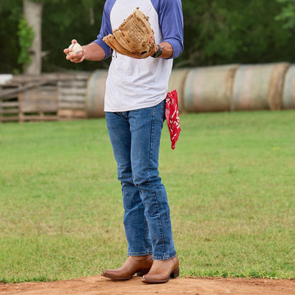Brown cowboy boots standing on grass, worn with jeans and a white shirt