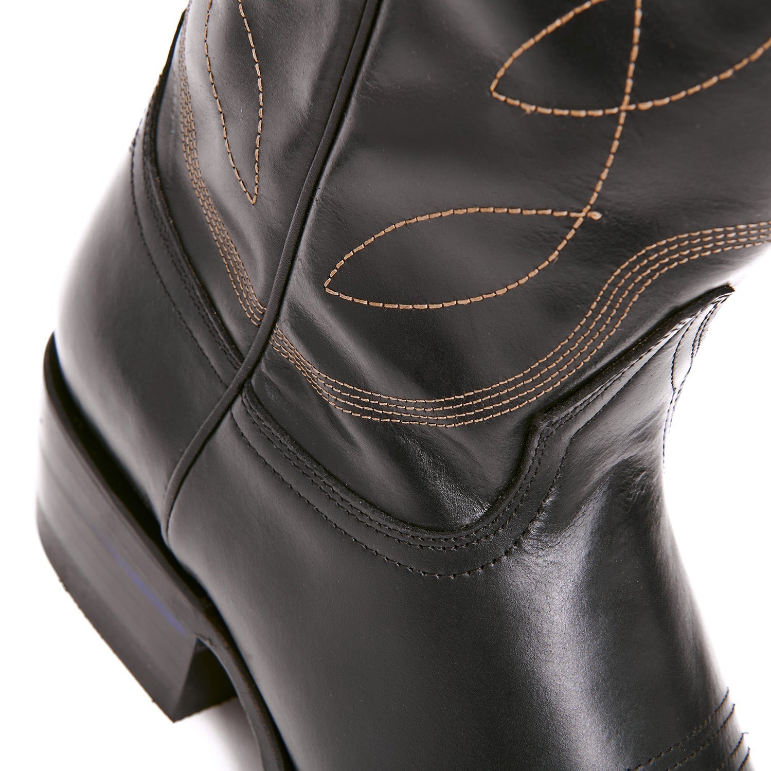 Black cowboy boot upper with tan stitch swirls near the ankle