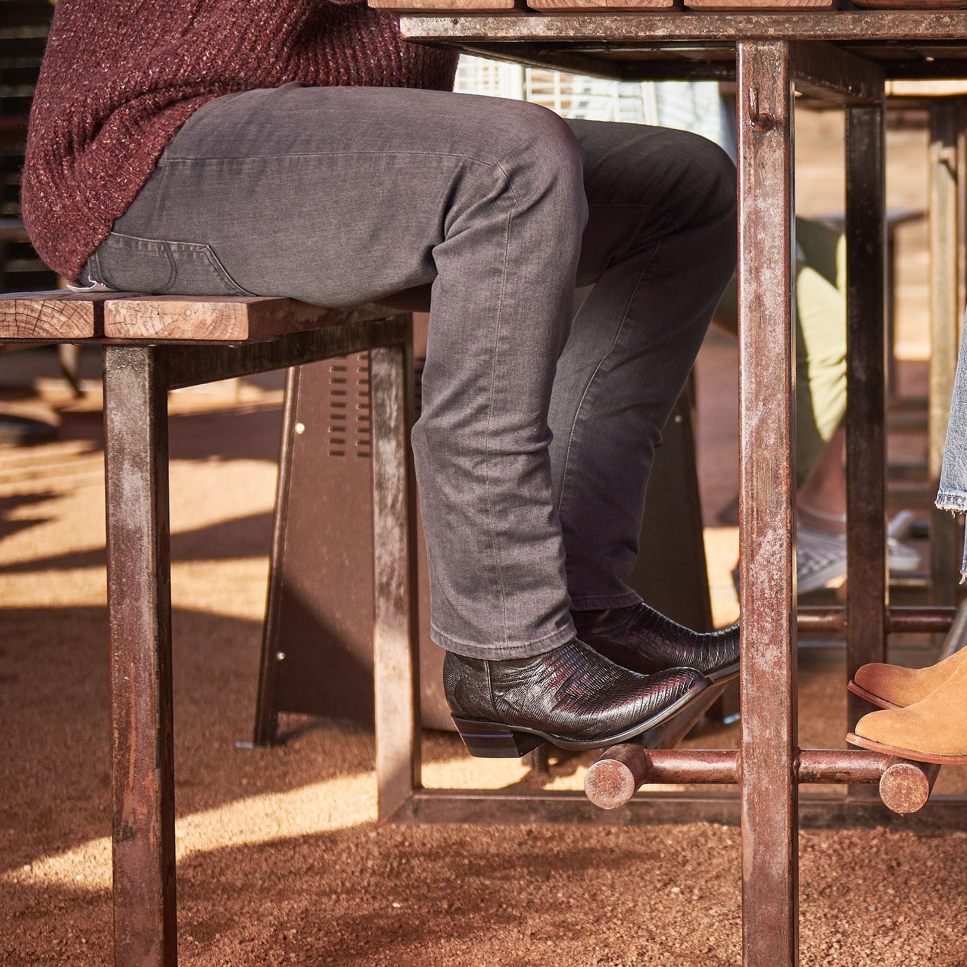 The Congress cowboy boots in dark brown leather worn with gray pants on porch