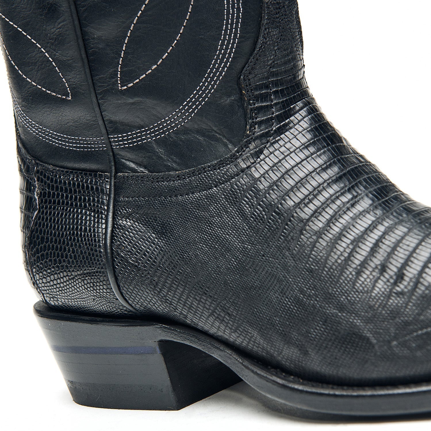 Black cowboy boot heel and side with textured leather and curved stitch accents.
