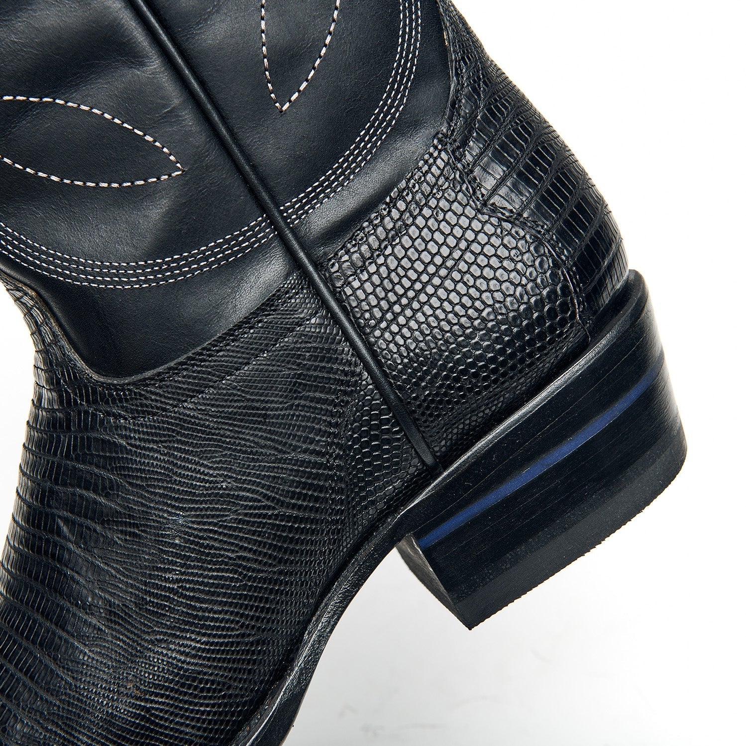 Black cowboy boot side detail with textured panel, contrast stitching, and stacked heel.
