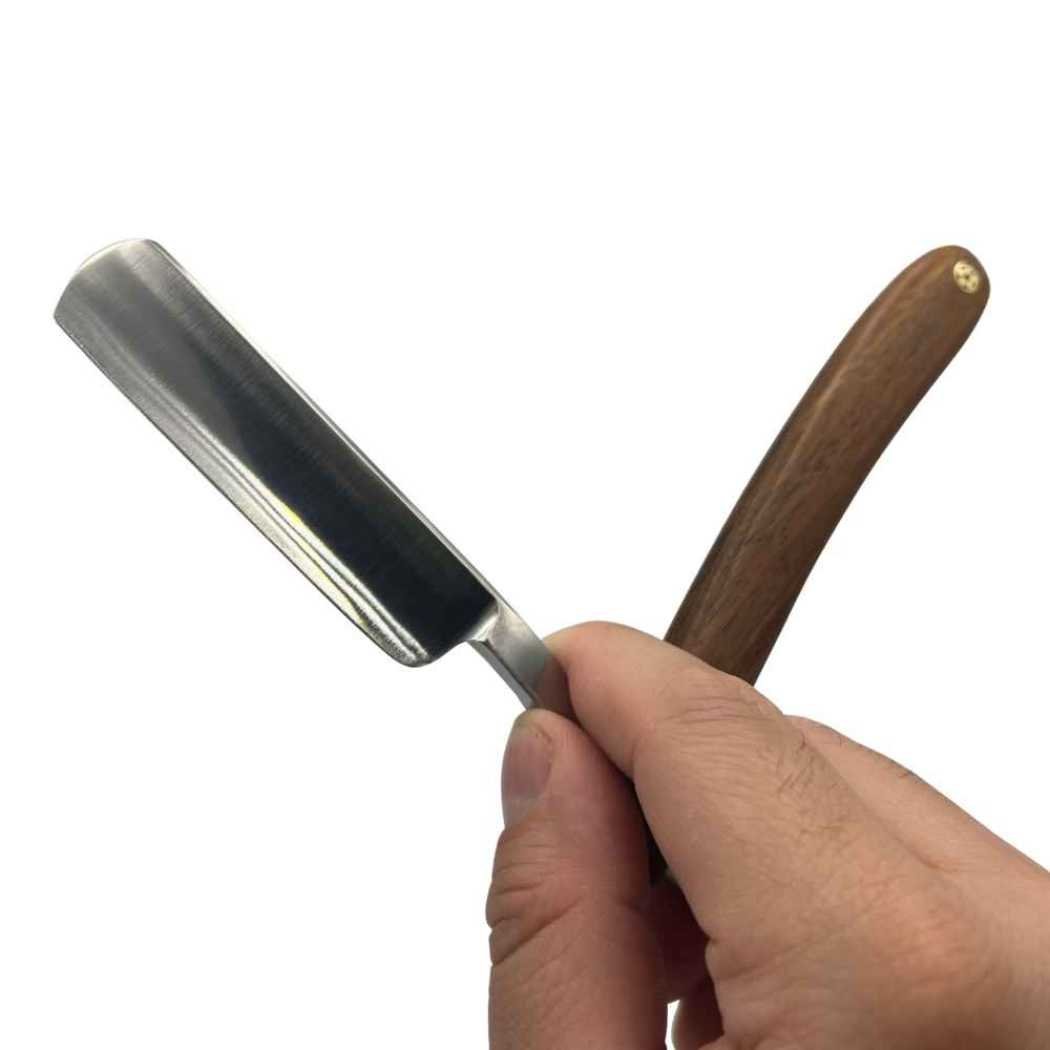 Straight razor with wooden handle held in hand, silver blade visible