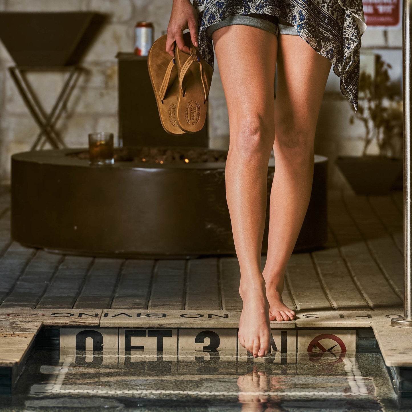 Flip-flops on bare feet with a tan-brown thong and brown sole, worn outdoors