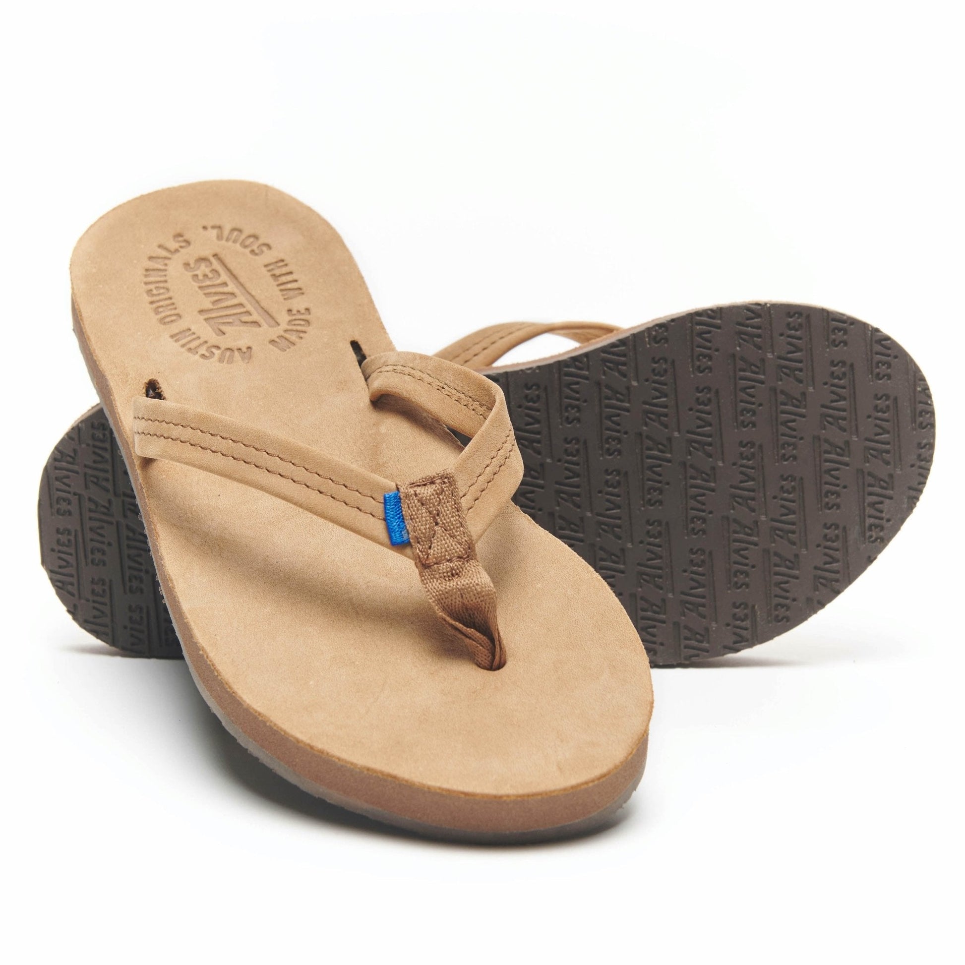 Tan flip-flops showing textured tread outsole on the dark rubber footbed