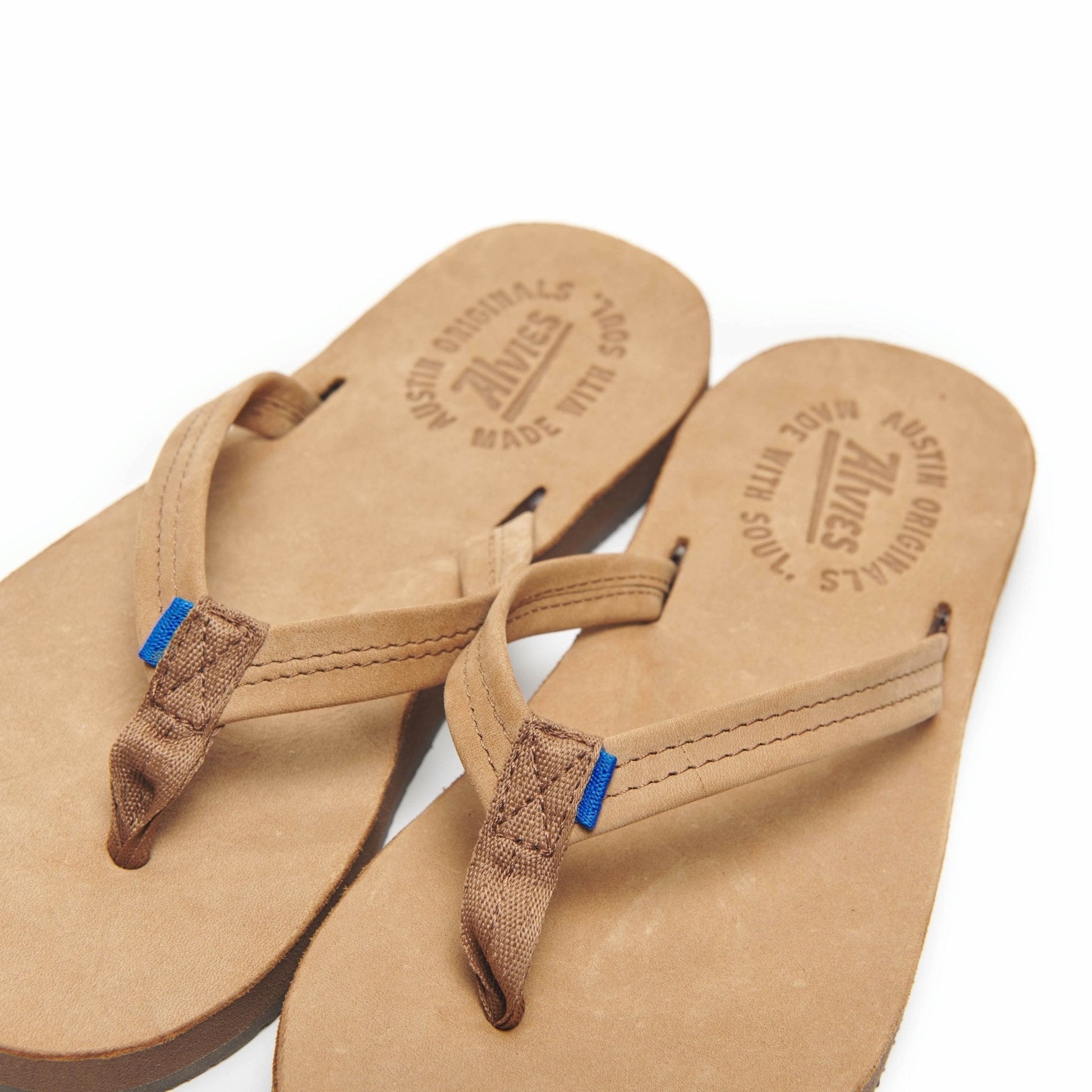 Tan flip-flops side by side with embossed insoles and brown straps