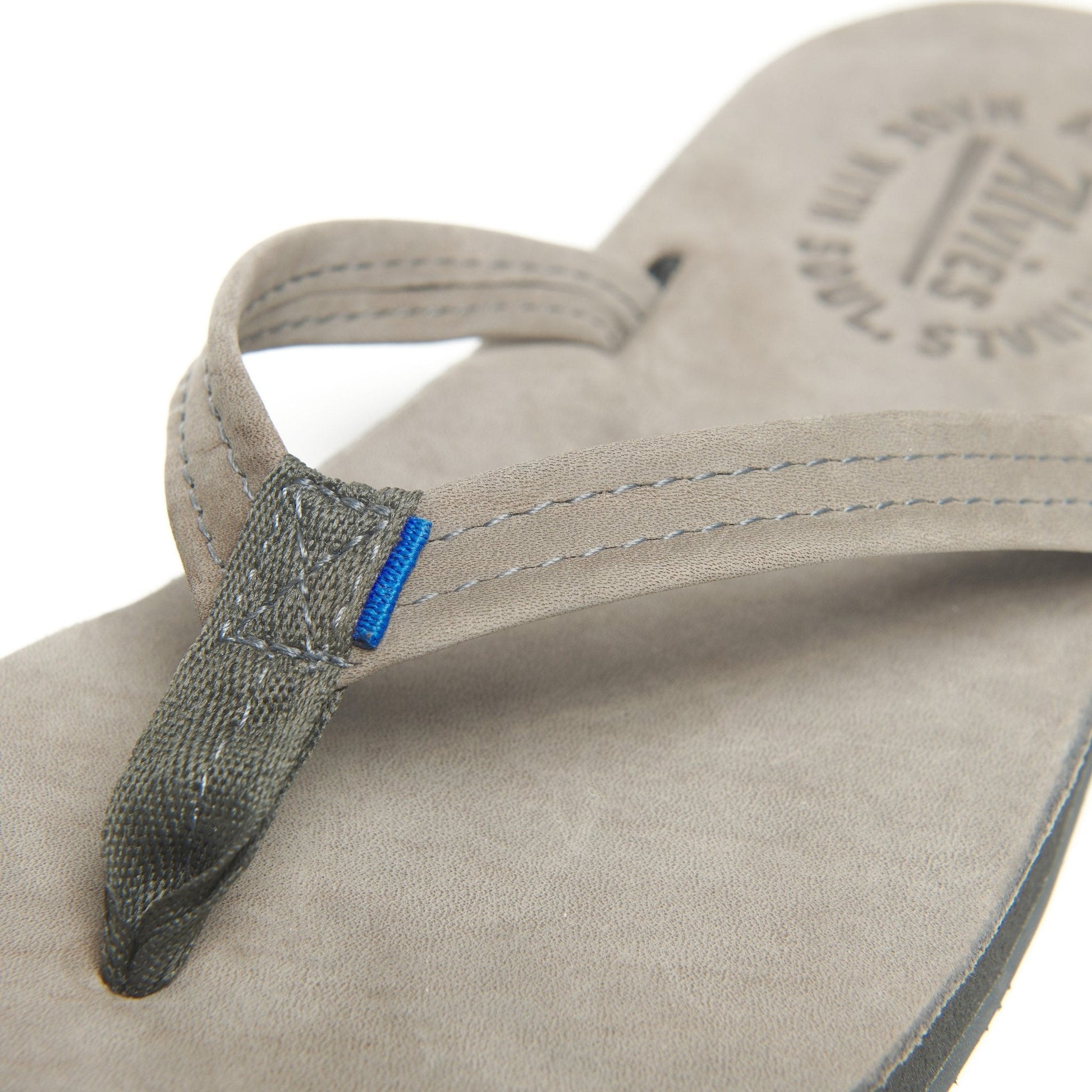 Close-up of suede flip-flop strap with gray top and blue accent tag