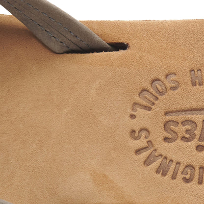 Close-up of tan flip-flop footbed with embossed logo and blue stitching detail