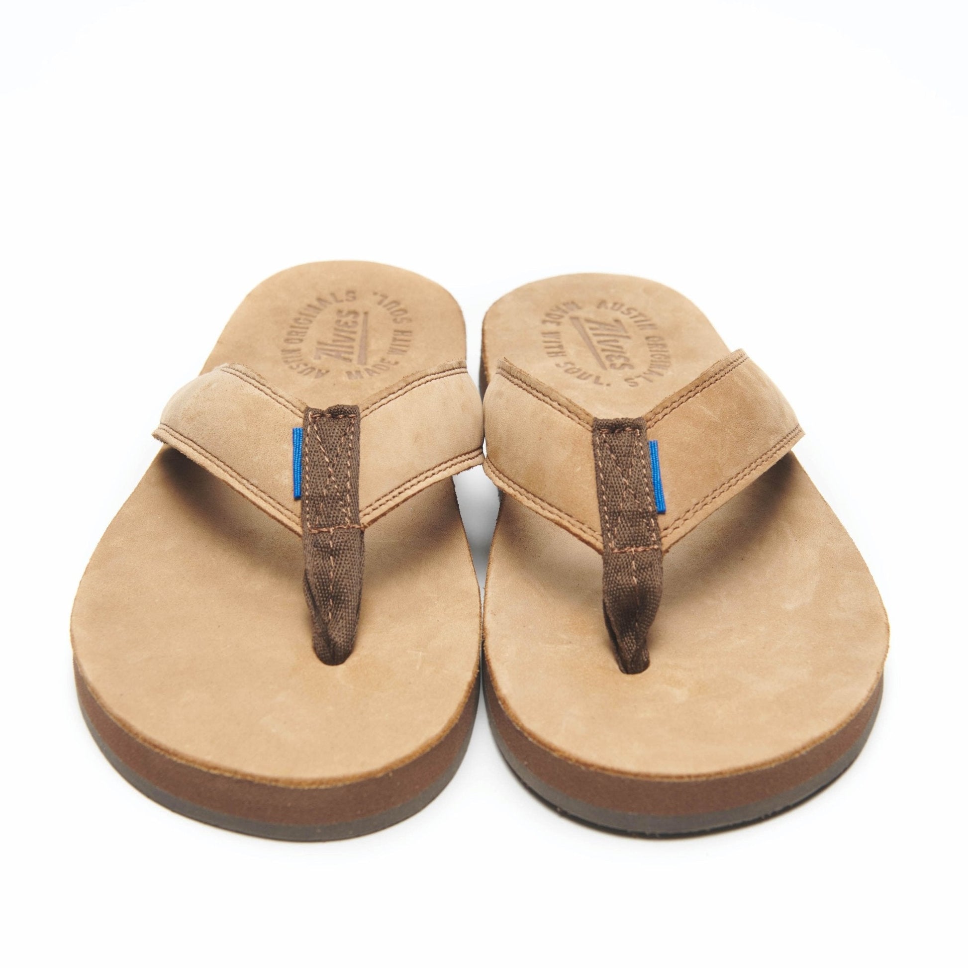Tan thong flip-flops with dark straps and blue accent stitching, top view