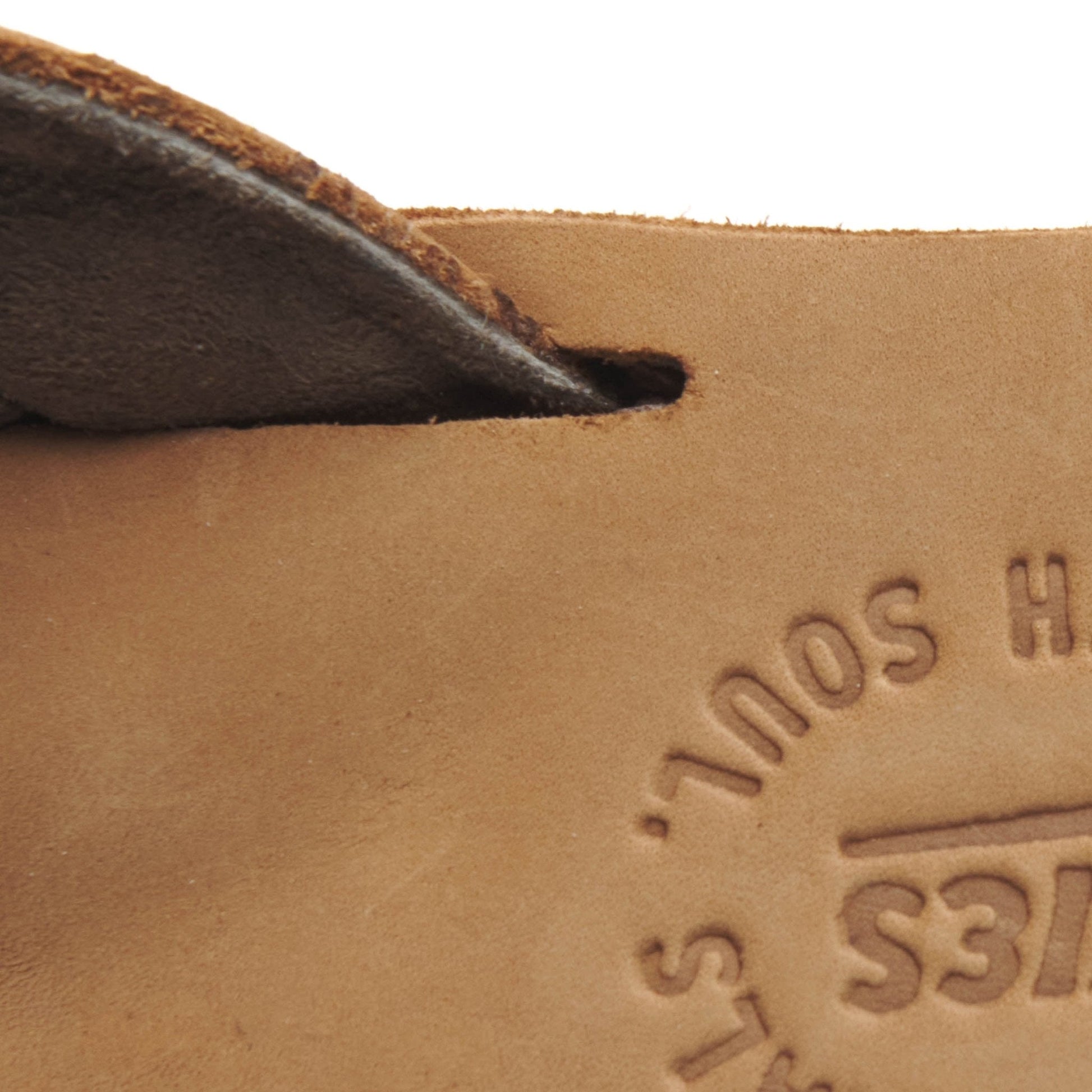 Tan suede thong strap detail with embossed logo text on footbed.