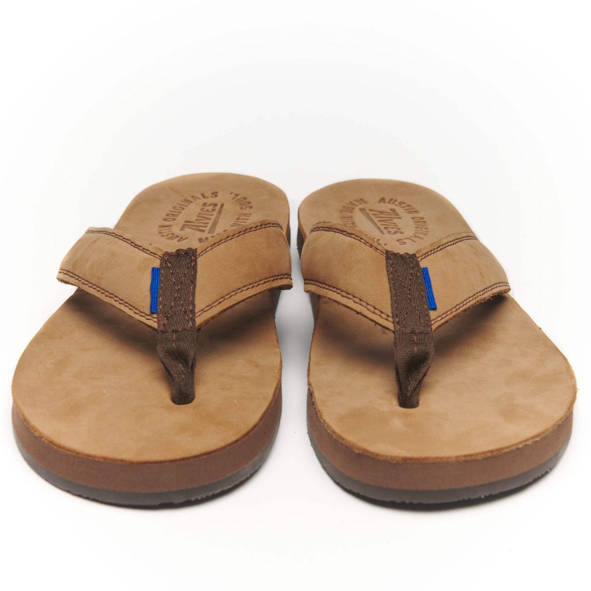Tan suede flip-flops with black thong straps and blue stitch accents.