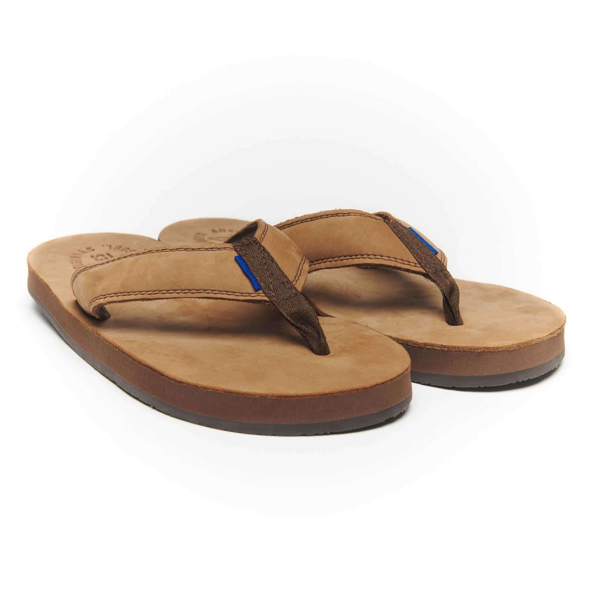 Pair of tan thong flip-flops with dark straps and blue detail stitching