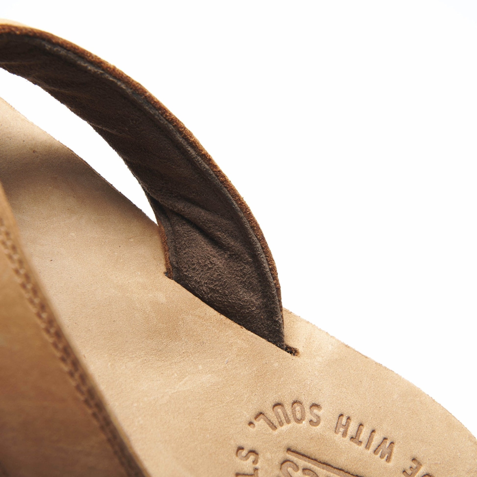 Tan flip-flop sandal close-up with brown strap and embossed logo on footbed
