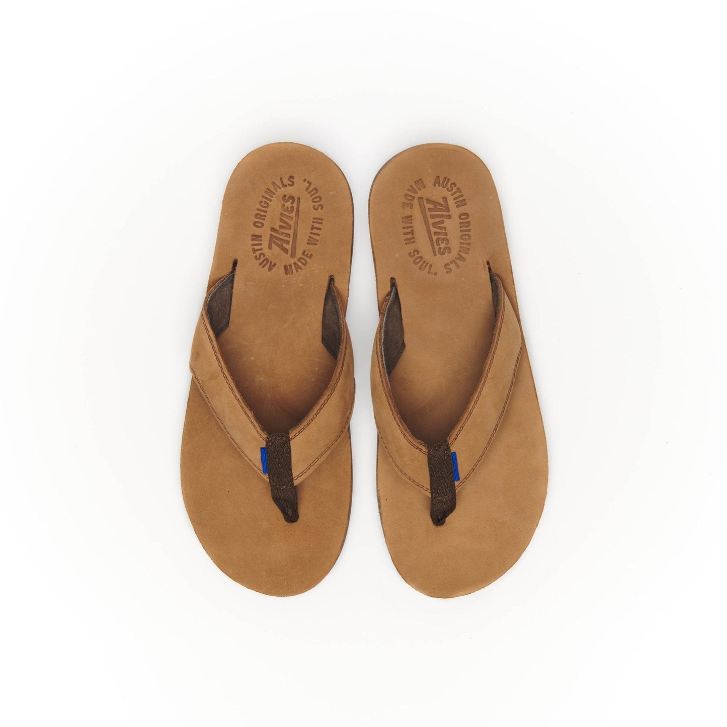 Pair of tan suede flip-flops with black thong straps and blue stitch accents.