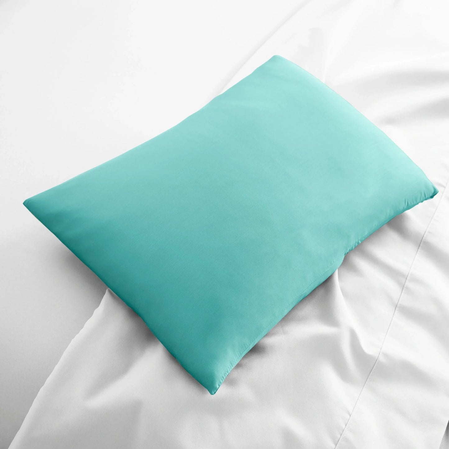 Turquoise travel pillowcase, smooth fabric folded on bed