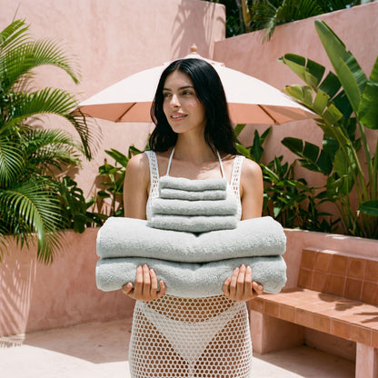 Stack of light gray cotton towels, neatly folded for bath use