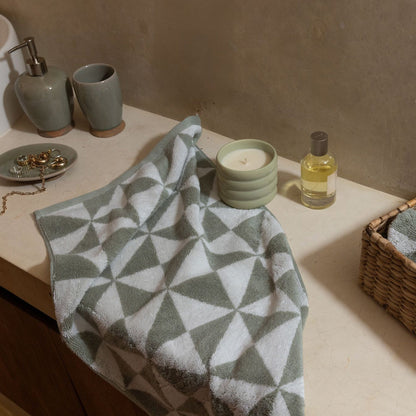 Cotton towels with sage and ecru triangle pattern on a tabletop