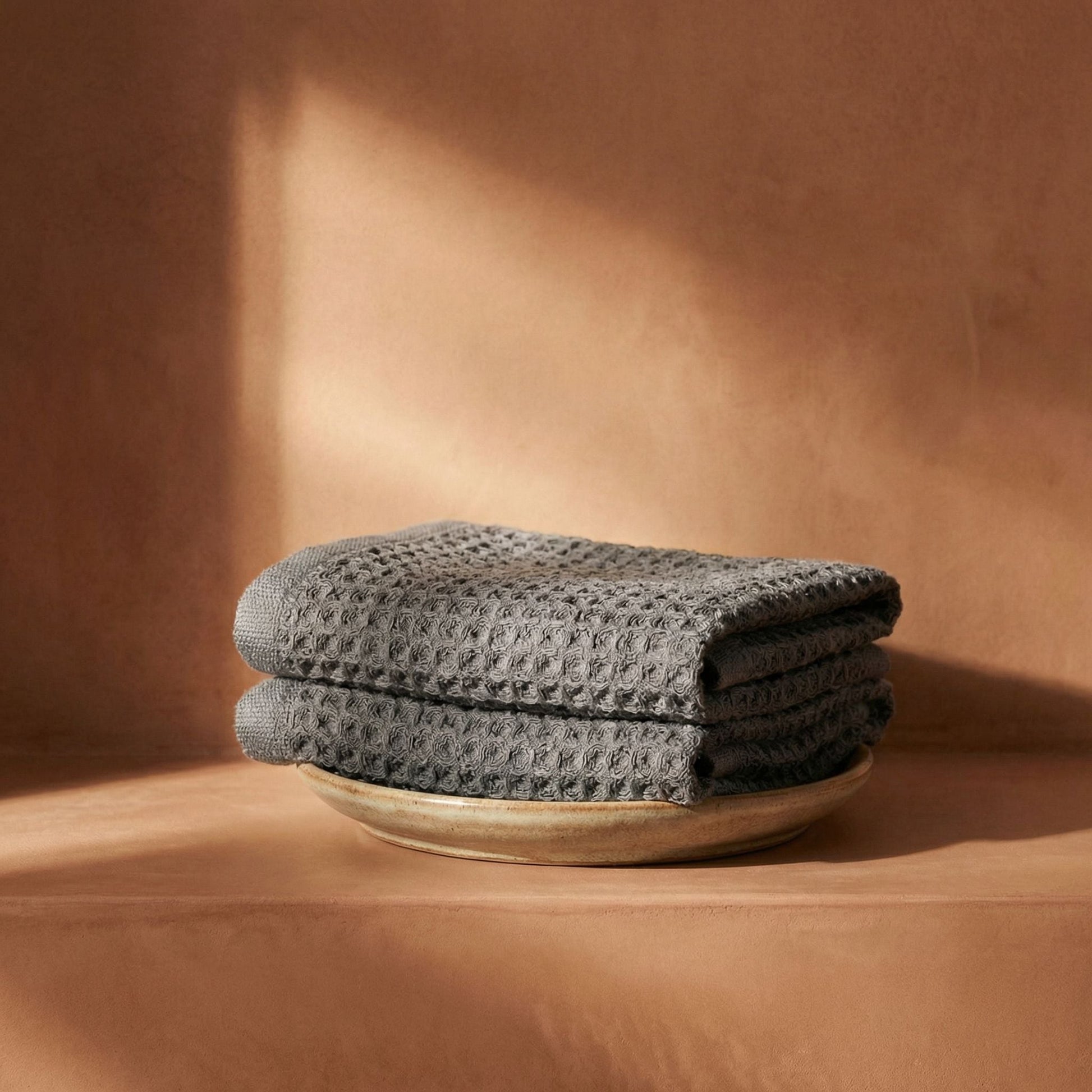 Charcoal waffle cotton towels rolled and stacked, visible waffle weave