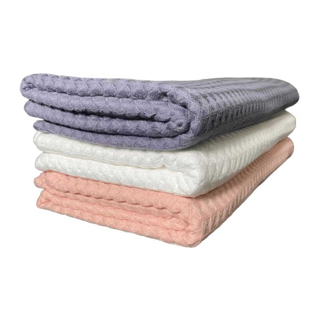 Waffle weave bath towel stack in charcoal gray, coral, and white.