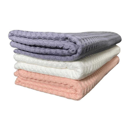 Waffle weave bath towel stack in charcoal gray, coral, and white.