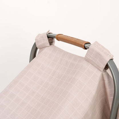 White muslin car seat cover with buttoned strap and folded corner detail