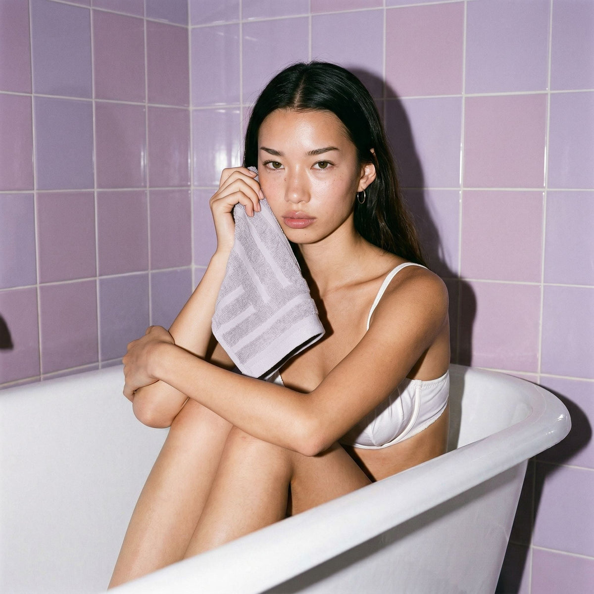Lilac cotton towel held near bathroom tiles