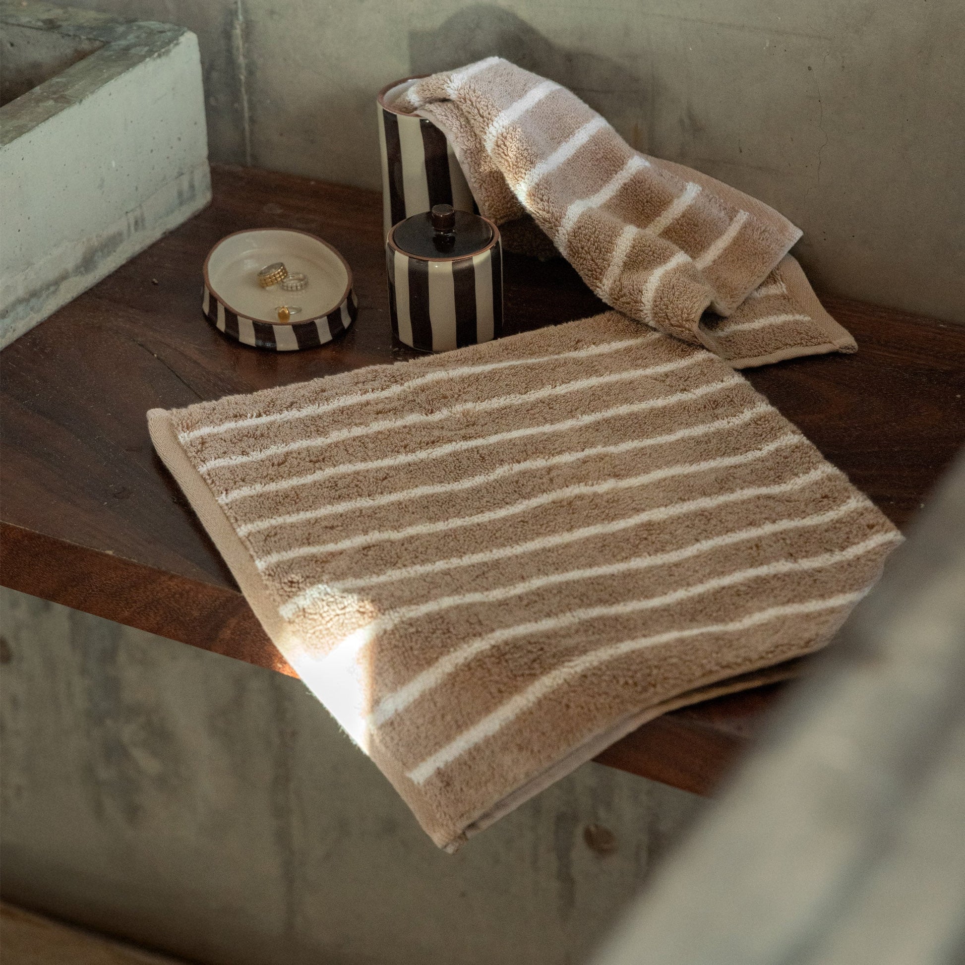 Striped towel and washcloth set on floor, beige and white plush cotton loops