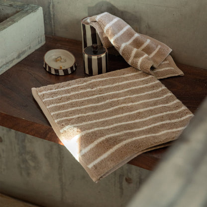 Striped towel and washcloth set on floor, beige and white plush cotton loops