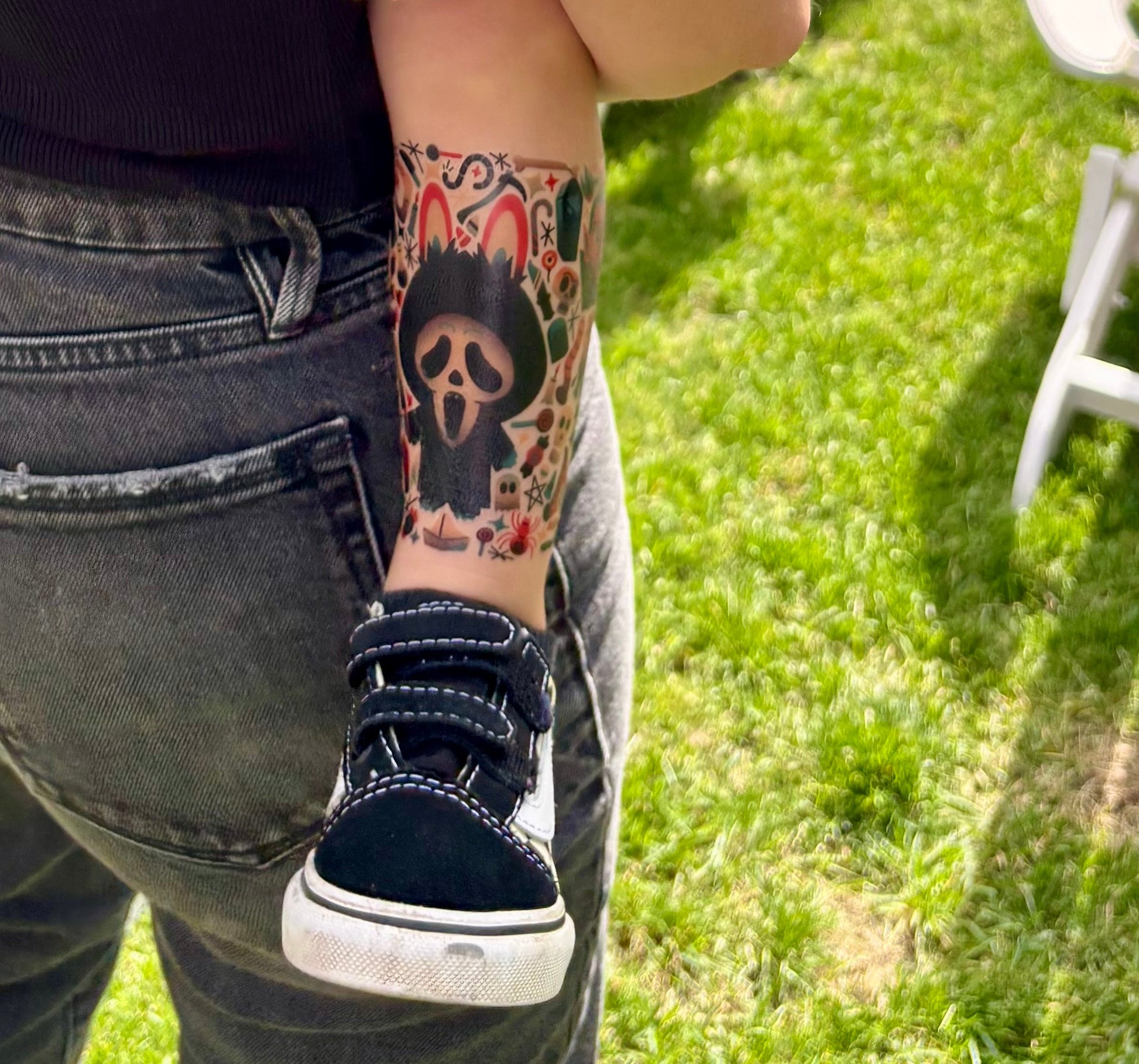 Temporary tattoo sleeve on lower leg, showing a black skull and red monster design