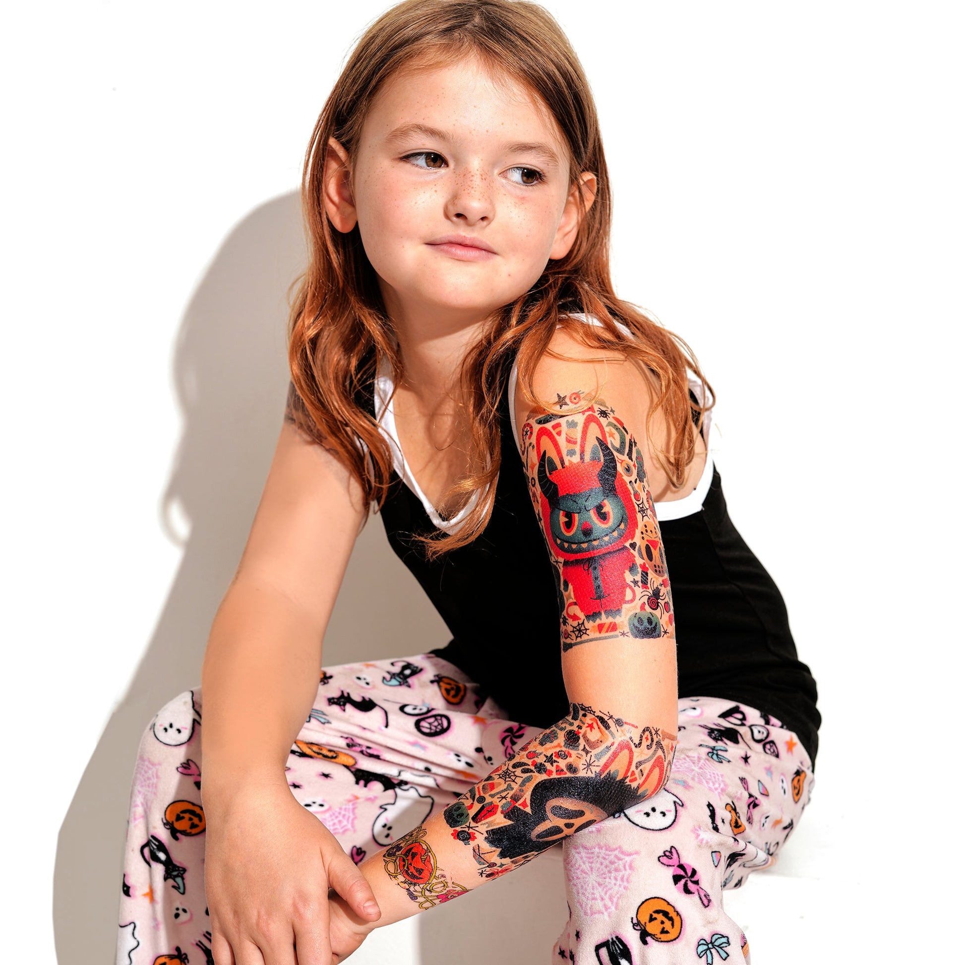 Kids temporary tattoo sleeve on forearm, featuring cat monster and skull art