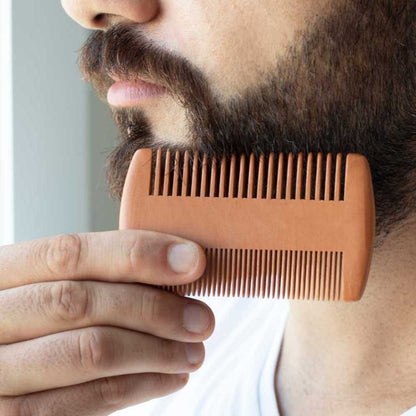 Wooden beard comb held against a man’s beard, showing fine teeth.