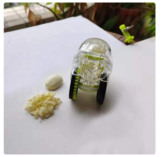 Rolling garlic chopper on a countertop with chopped garlic pieces and clear housing