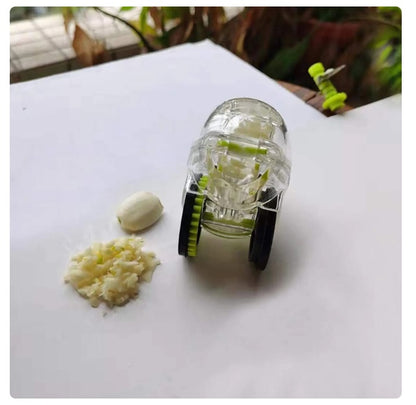 Rolling garlic chopper on a countertop with chopped garlic pieces and clear housing