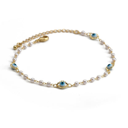 Gold charm bracelet with white pearl-like beads and a blue evil-eye center charm