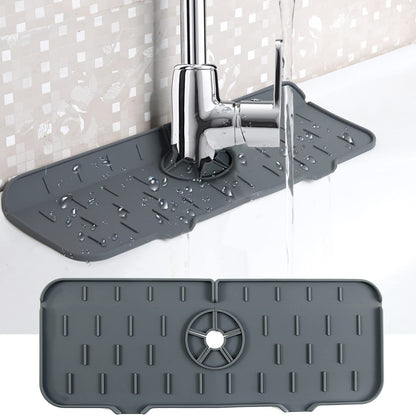 Grey kitchen faucet mat with raised ridges and a circular drain wheel near faucet