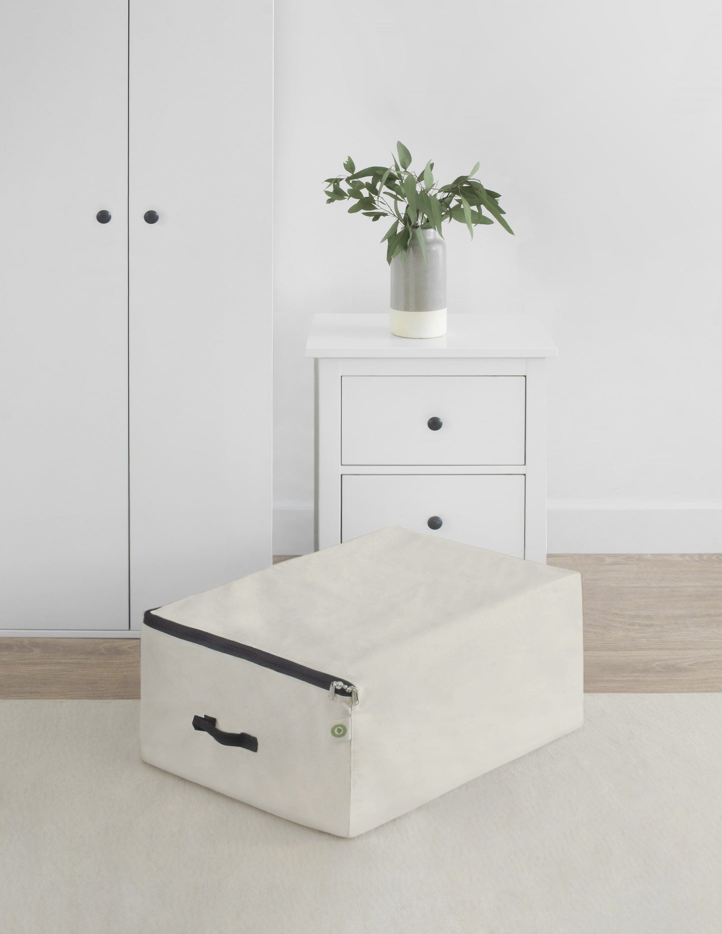 Comforter storage bag, beige folded with front zipper and small green label